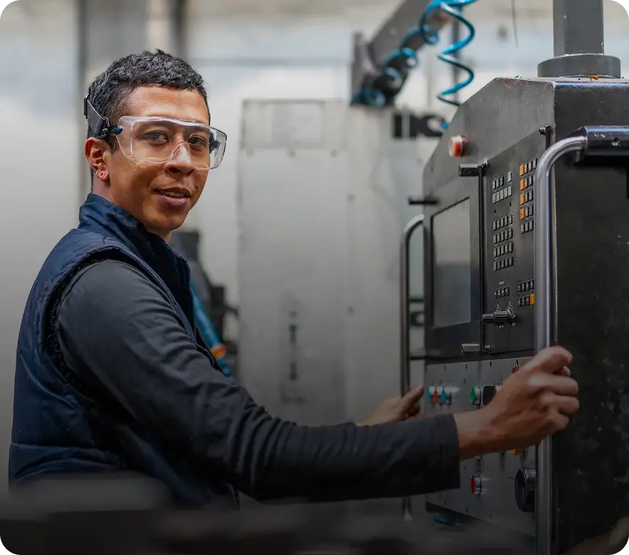 Worker operating an industrial machine, wearing goggles.